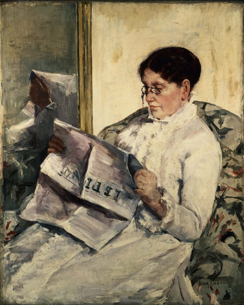 A woman in an armchair reading a newspaper